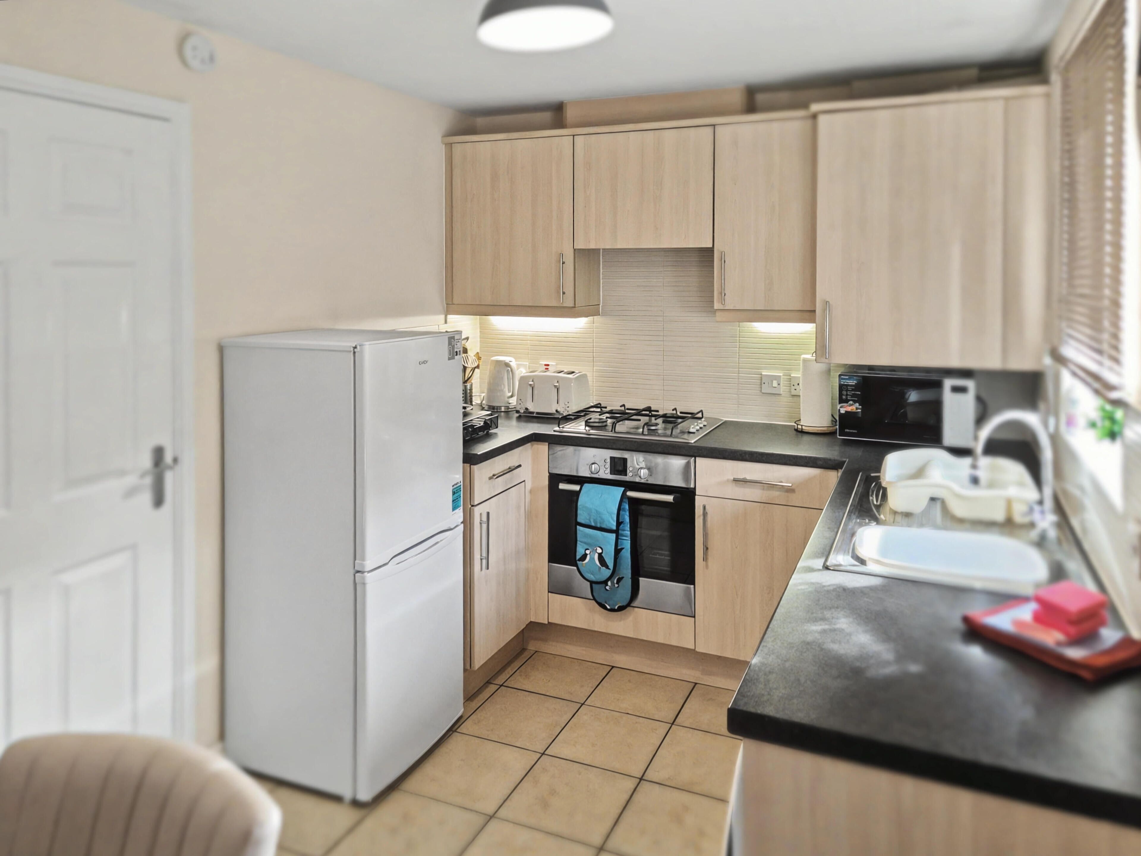 A compact kitchen with a refrigerator, stove, oven, and microwave.