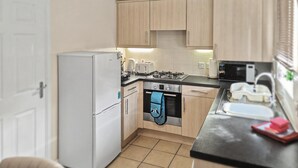 A compact kitchen with a refrigerator, stove, oven, and microwave. - Stylish 2BR Solihull Stay | Near NEC | Parking | Garden (Solihull)