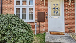 A brick house with a white door, two windows, and a small porch. - Stylish 2BR Solihull Stay | Near NEC | Parking | Garden (Solihull)