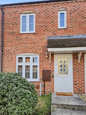 A brick house with a white door, two windows, and a small porch.