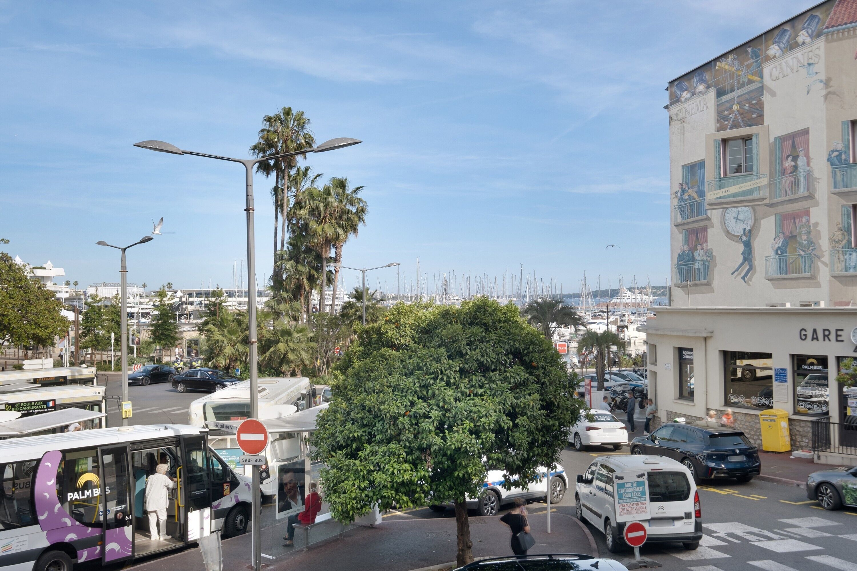 A street scene with a bus, cars, and a building with a sign that reads 'CANNES.'