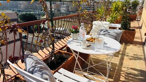 Ein Balkon mit Tisch für zwei Personen, einem Blumentopf und Blick auf eine Brücke.