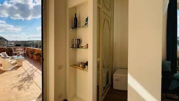 Quarto com janela ampla, cama, mesa de cabeceira e vista da cidade.