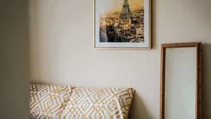 A bed with patterned bedding, a framed picture of the Eiffel Tower, and a mirror on the wall. - Charming house with Garden in Aylesbury (Aylesbury)