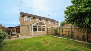A two-story house with a covered patio, a fenced backyard, and a wooden fence. - Charming house with Garden in Aylesbury (Aylesbury)
