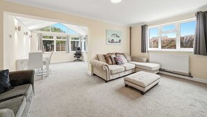 A spacious living room with a large window, a sofa set, a dining area, and a radiator. - Charming house with Garden in Aylesbury (Aylesbury)
