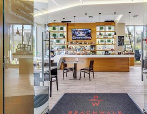 A modern bar area with a TV screen, wooden counter, and seating. - Stylish Studio w/ Intracoastal & Sunset Views (Hallandale Beach)