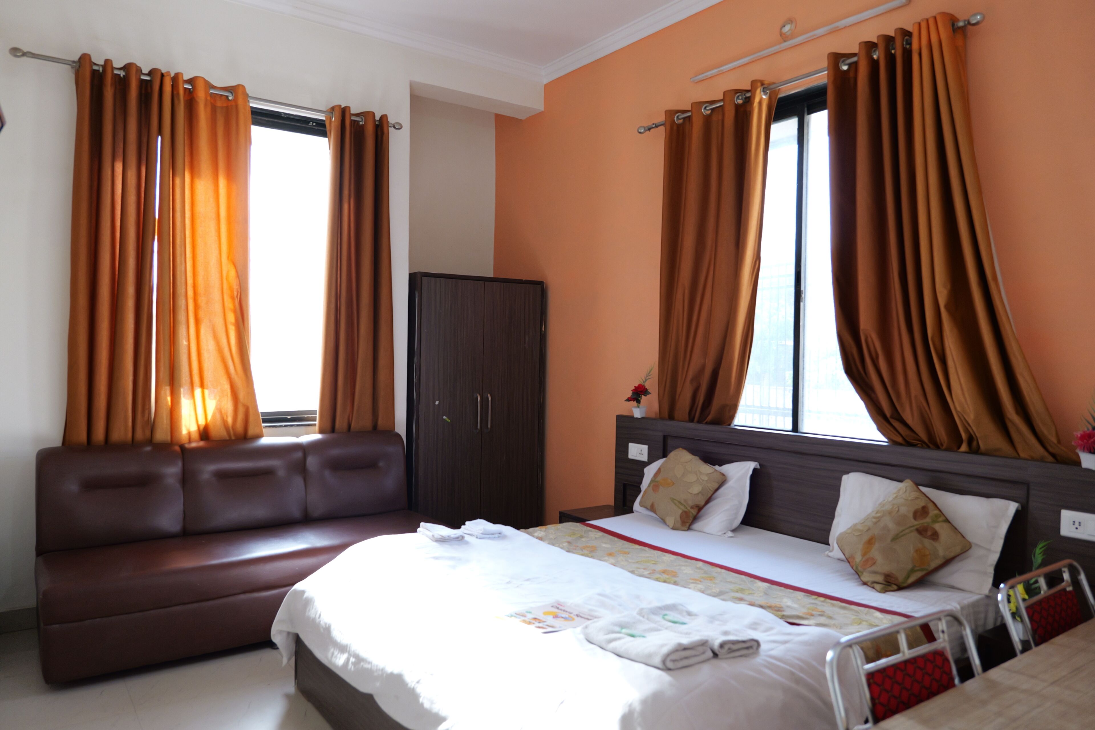 Une chambre d’hôtel avec un lit, un canapé, une armoire et des rideaux.