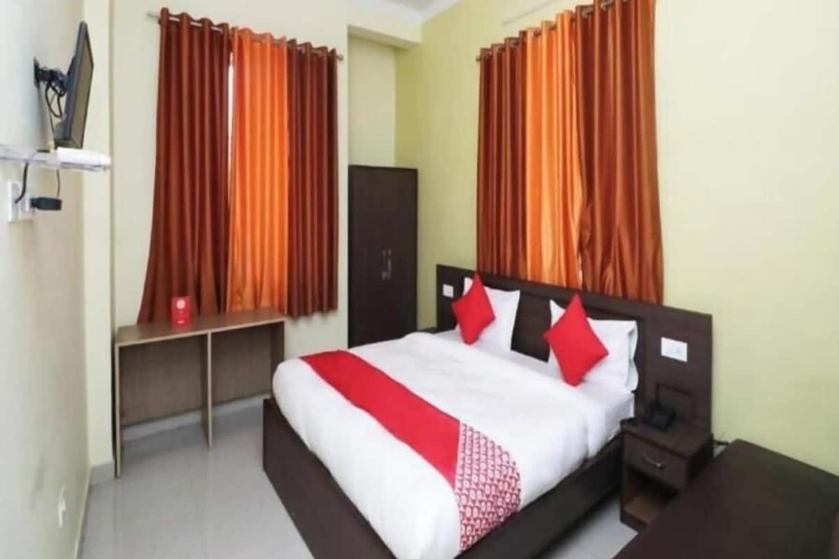 Una habitación de hotel con cama, escritorio, armario y cortinas.