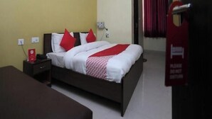 Una habitación de hotel con cama, mesita de noche y aire acondicionado en la pared.