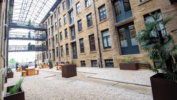 A spacious atrium with a high ceiling, multiple floors, and a central open area with seating and planters. - Charming 2-bedroom Apartment in Bradford With City Views (Bradford)