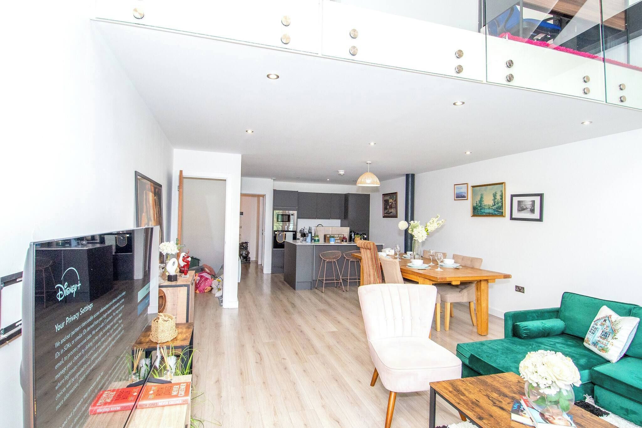 A modern living room with a TV, dining area, and kitchen in the background.