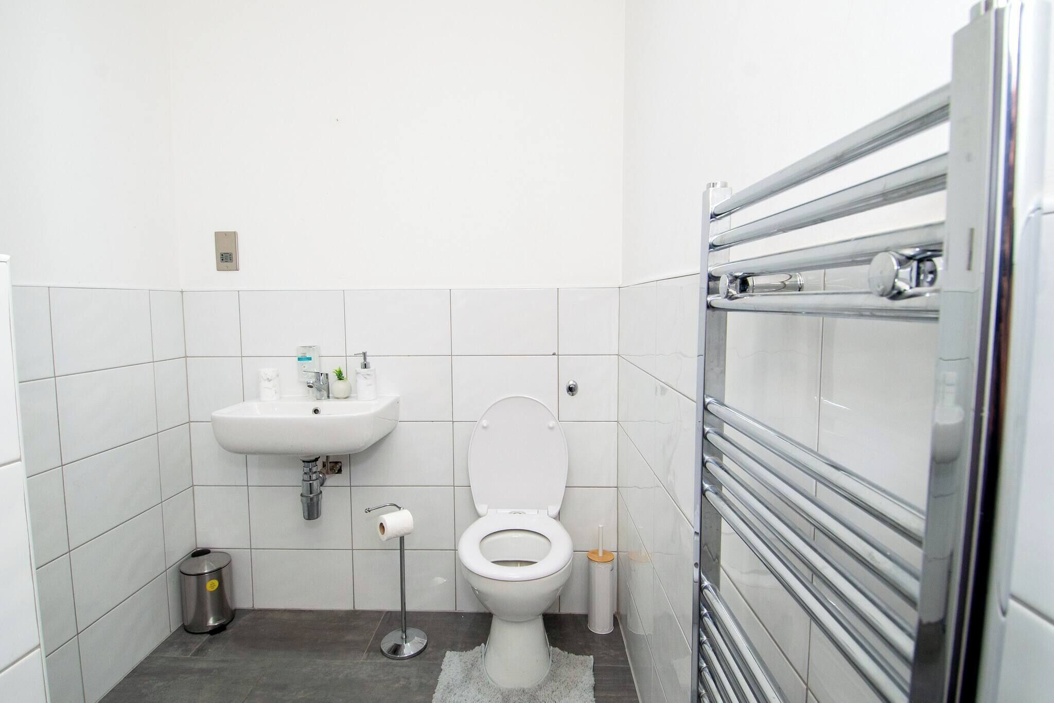 A small, modern bathroom with a toilet, sink, and hand dryer.