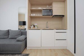 A compact kitchen with a microwave, cabinets, and a sink. - A comfortable studio near PGE Narodowy | A place to work (Warszawa)