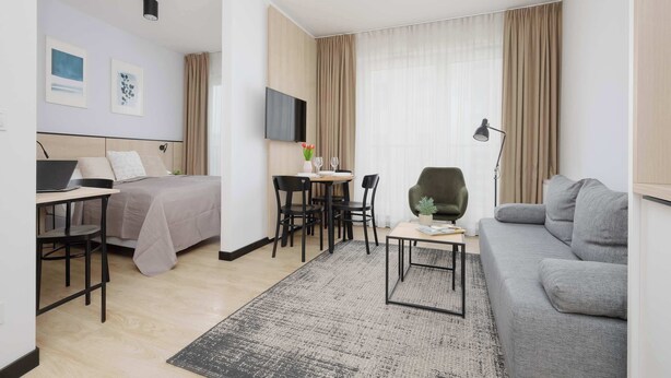 A modern hotel room with a bed, desk, and sofa. - A comfortable studio near PGE Narodowy | A place to work (Warszawa)