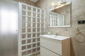 Ein Badezimmer mit Glasdusche, Waschbecken und Spiegel.