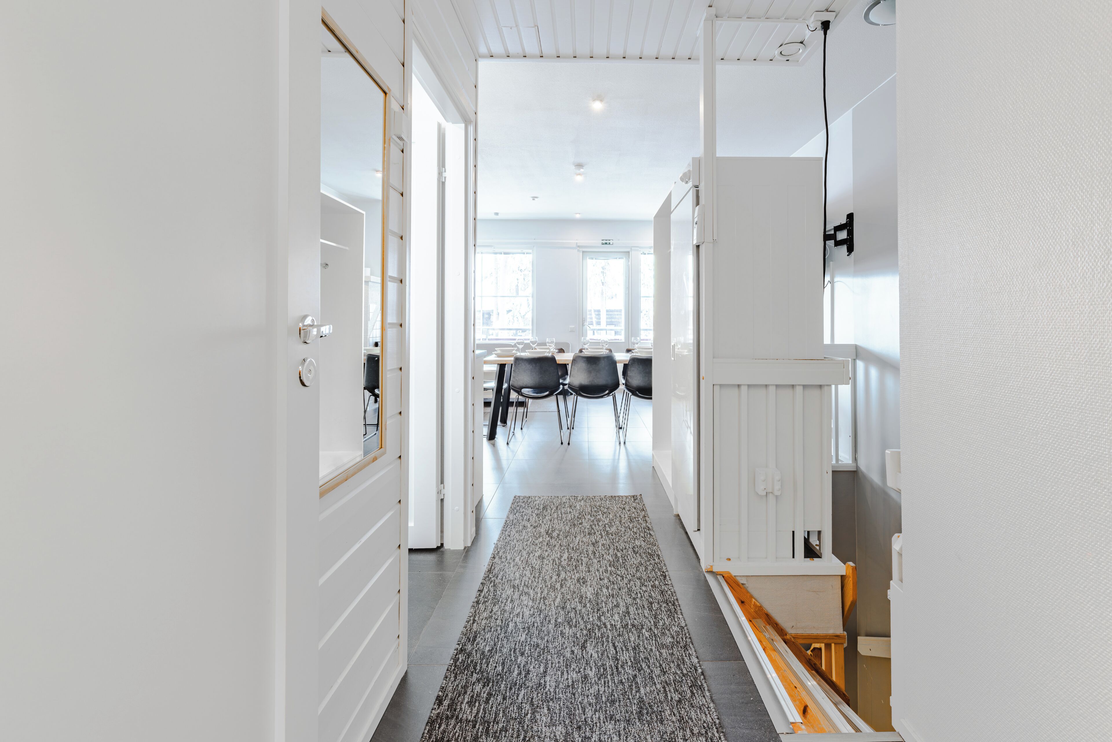 A hallway with white walls, a grey carpet, and a wooden bench.