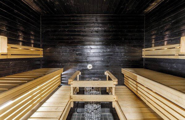 A sauna with wooden benches and a central fire pit.