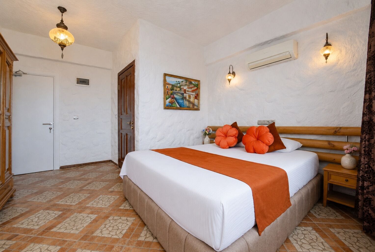 A bedroom with a bed, a painting, a nightstand, and a door.