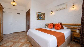 A bedroom with a bed, a painting, a nightstand, and a door.