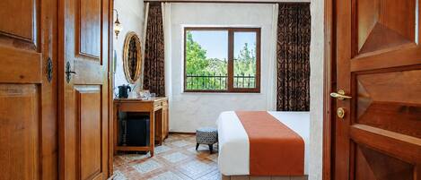 Une chambre d’hôtel équipée d’un lit, d’un bureau, d’une chaise, d’une fenêtre donnant sur un paysage agréable et d’une armoire.