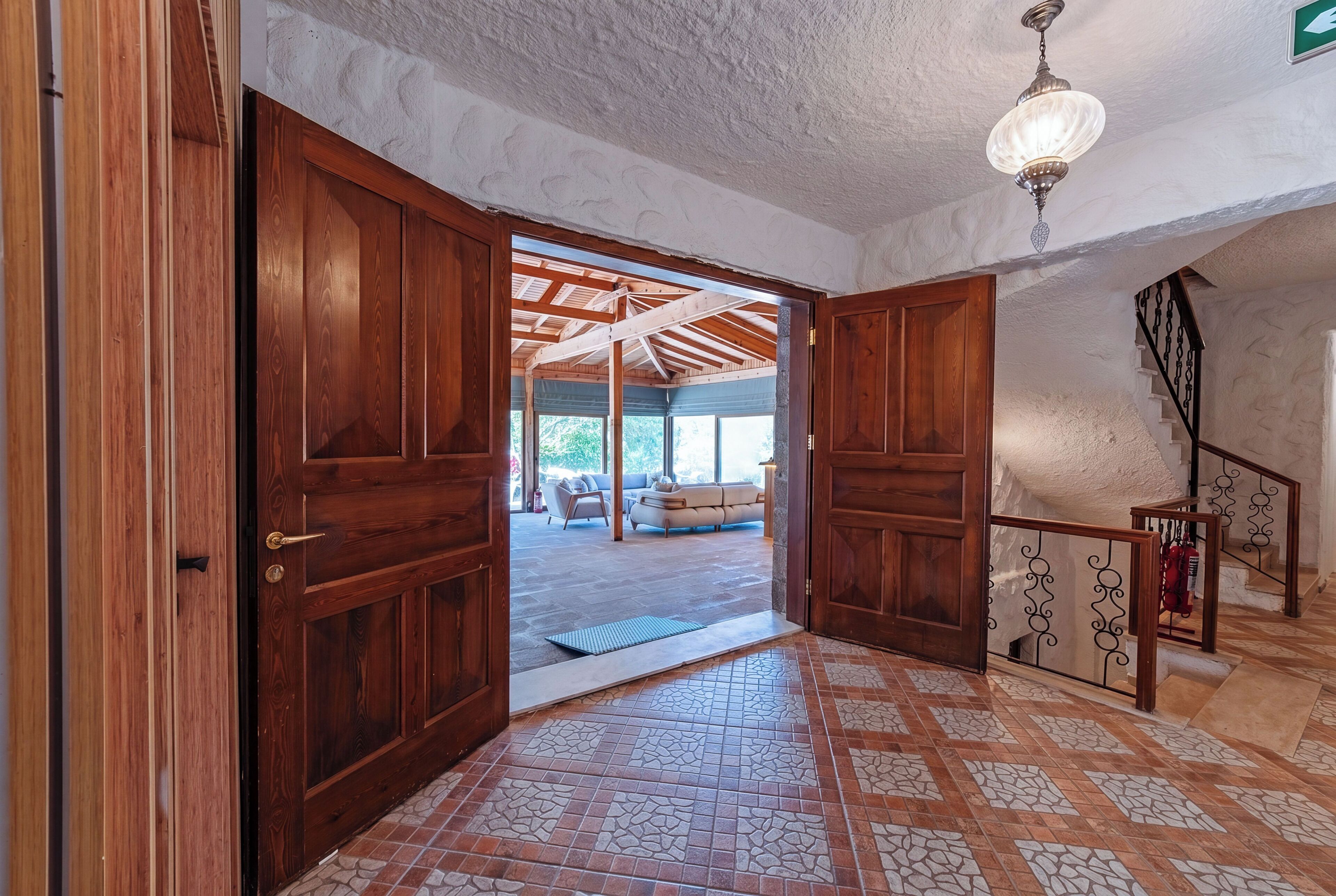 Una puerta de madera que da a un cuarto con piso de baldosas y un ventilador de techo.