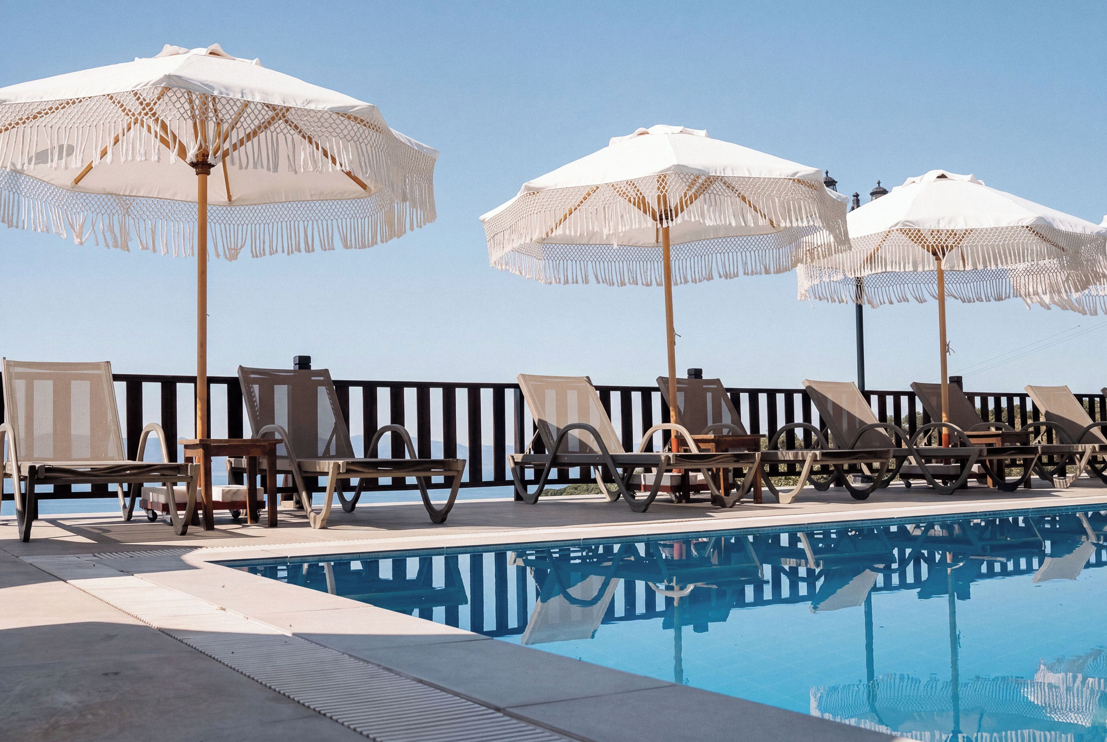 A poolside area with lounge chairs and white umbrellas.