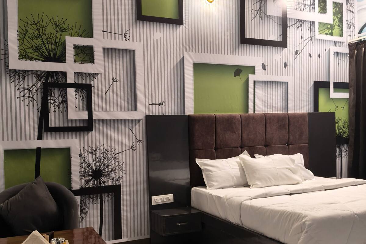 Un dormitorio moderno con cama, mesita de noche, silla y pared con patrones geométricos y detalles en verde.