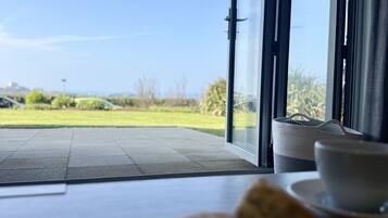 A dining area with a view of the outdoors, a table with a plate of scones, and a basket.