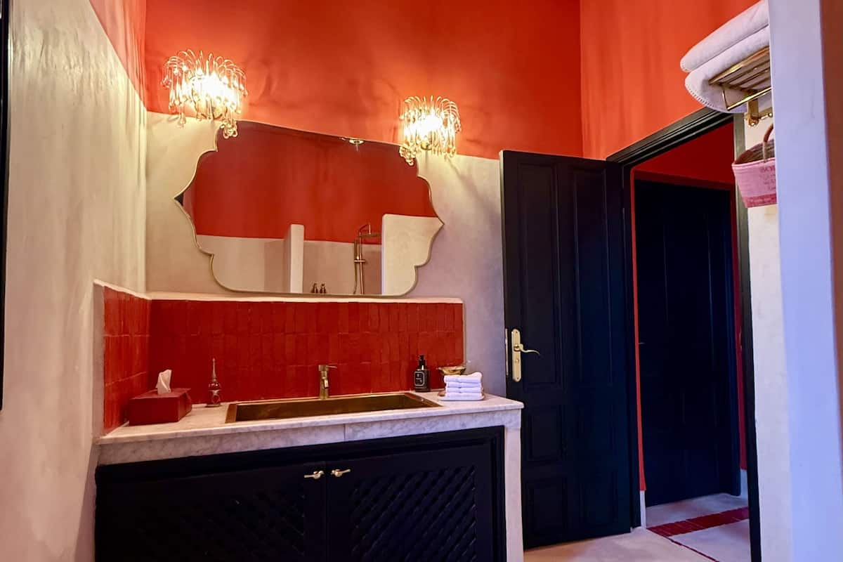 A bathroom with a red and white color scheme, a black cabinet, a mirror, and a red rug.