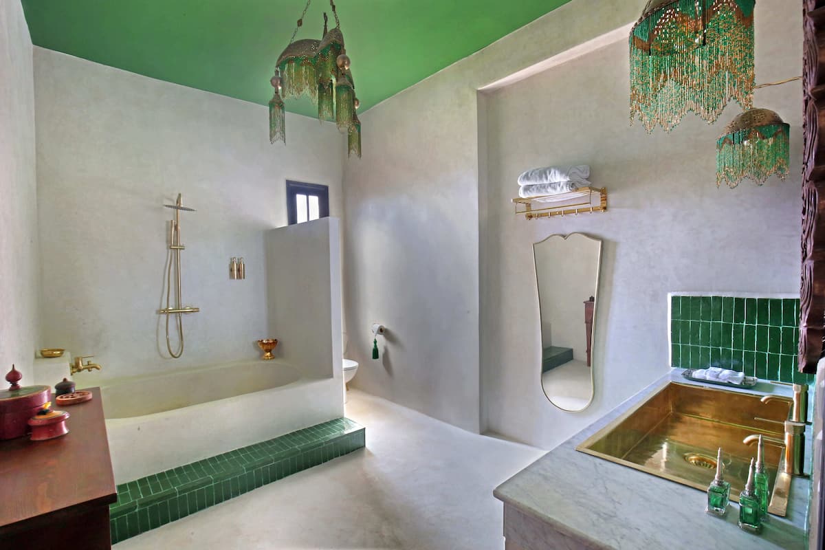 A bathroom with a bathtub, shower, and sink, with green tiles and a mirror.