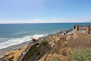 A coastal walkway with a wooden staircase leading down to the beach, a lookout point, and a fenced area with a bench. - Sunset Passage - Top floor corner unit with ocean views (Solana Beach)