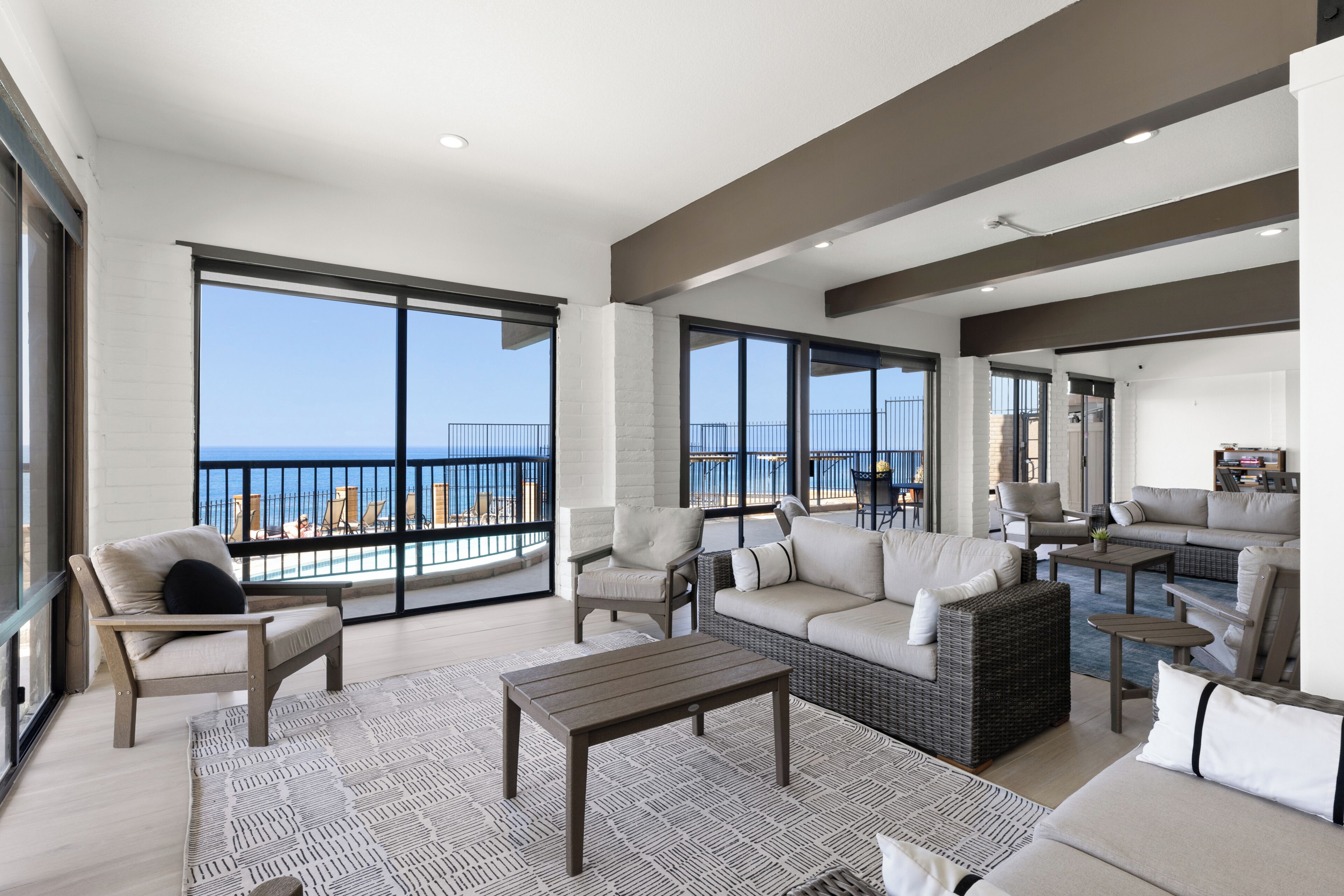 Ein geräumiger Wohnbereich mit einem Balkon mit Meerblick, ausgestattet mit Sofas, Sesseln und einem Couchtisch.