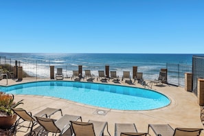 A curved pool with lounge chairs and a view of the ocean. - Sunset Passage - Top floor corner unit with ocean views (Solana Beach)