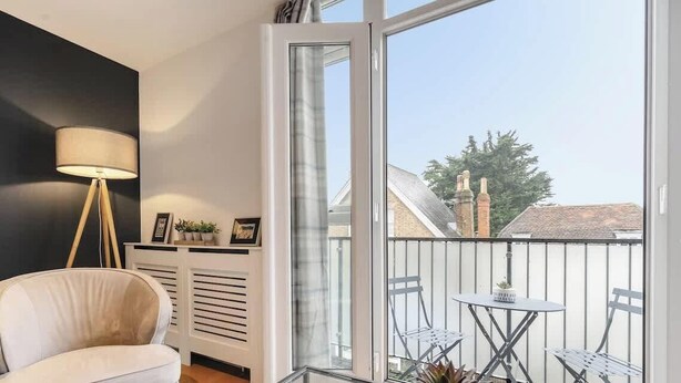 A balcony with a white chair, a small table, and a floor lamp. - Charming 1BR Apartment | Parking Included (Windsor)