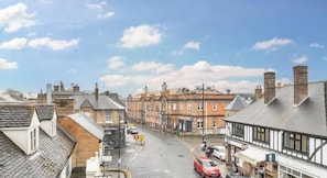 A street view with buildings, a clear sky, and a car on the road.