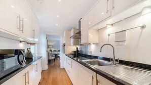A modern kitchen with white cabinets, black countertops, and stainless steel appliances. - Charming 1BR Apartment | Parking Included (Windsor)