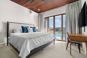 Un dormitorio con cama, televisor, mesa de comedor y vistas al exterior.