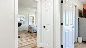 A hallway with wooden flooring, white doors, and a ceiling light fixture.