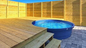 A wooden deck with a hot tub and a wooden fence.