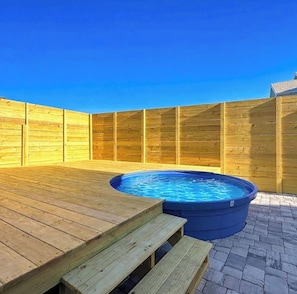 A wooden deck with a hot tub and a wooden fence.