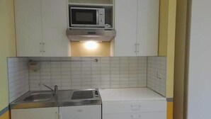Et lille køkken med mikroovn, vask og skabe.