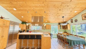 Eine Küche mit Holzausbau, einem Edelstahlkühlschrank, einer Bar und einem Esstisch mit Stühlen.
