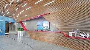 A modern reception area with a sloped ceiling, a reception desk, and a wall-mounted digital display. - Cozy Modern 1BR - Outdoor Space & Beach Access (Hallandale Beach)