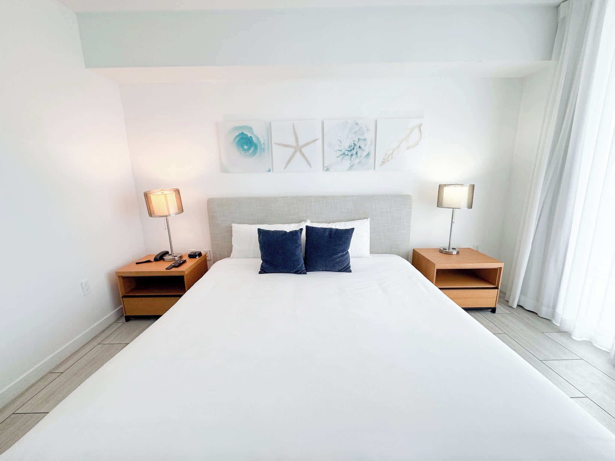 Ein großes Bett mit zwei Nachttischen, jeweils mit einer Lampe, in einem Raum mit schlichtem, klarem Design.