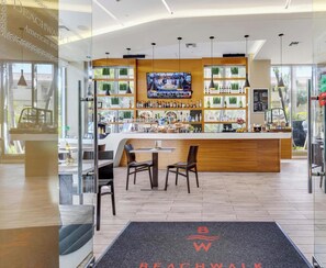 A bar area with a TV screen, shelves with bottles, and seating. - High Floor Studio w/ Balcony & Shuttle (Hallandale Beach)
