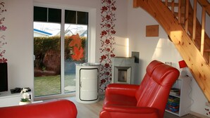 A room with a red leather chair, a white barrel, and a wooden staircase. - Holiday Home Jan Groen 8 (Wurster Nordseeküste)
