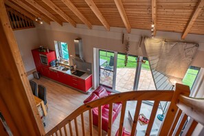 A modern kitchen with red cabinets, a stainless steel range hood, and a large window overlooking a patio. - Holiday Home Jan Groen 8 (Wurster Nordseeküste)