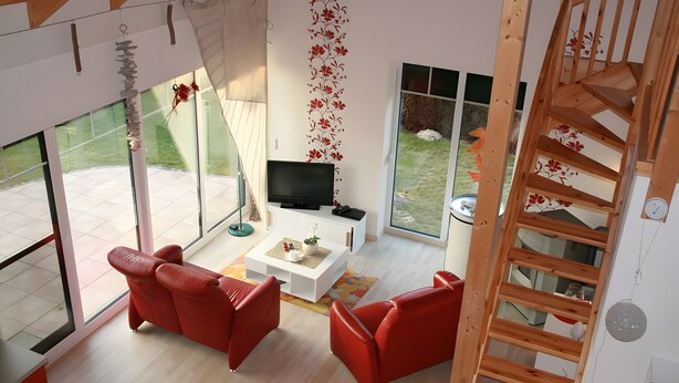 A modern living room with a TV, red sofas, a white coffee table, and a wooden staircase. - Holiday Home Jan Groen 8 (Wurster Nordseeküste)