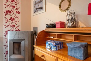 A room with a wooden dresser, a framed picture, a mirror, and a decorative wall with floral wallpaper. - Holiday Home Jan Groen 8 (Wurster Nordseeküste)